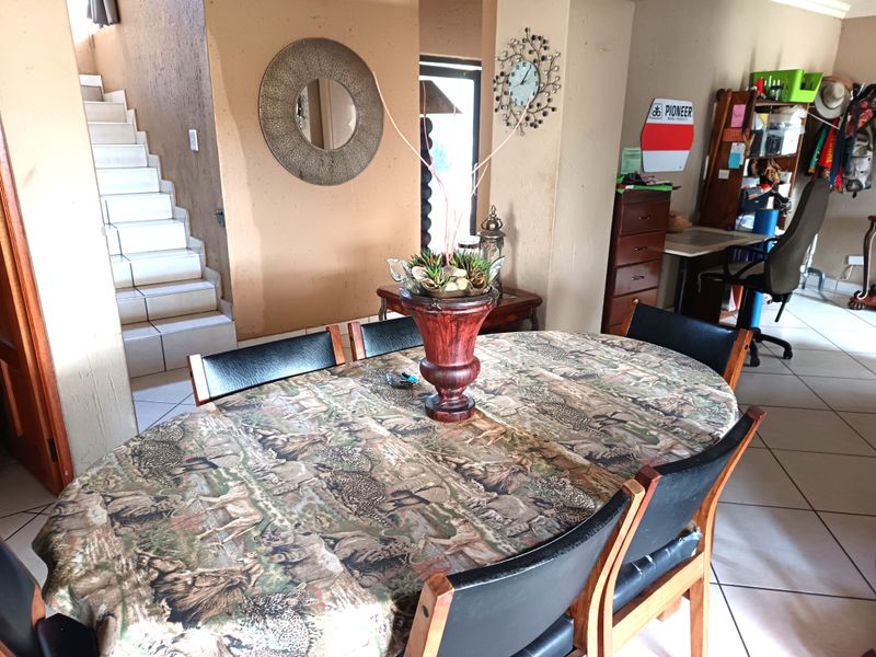Dining area featuring tiled flooring and an adjacent staircase, providing an open-plan layout with neutral wall finishes.