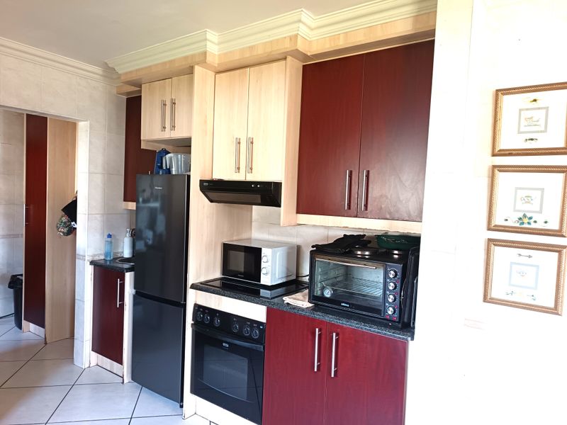 A functional kitchen featuring two-tone cabinetry, granite countertops, built-in oven, electric hob, extractor fan, and tiled flooring.