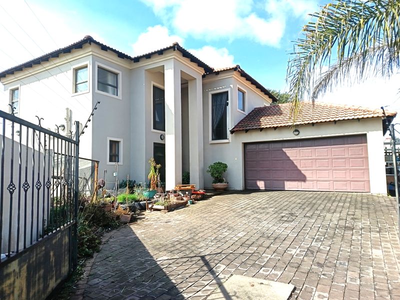 Front view of a two-story residential property featuring a paved driveway, double garage, and secure gated entrance.