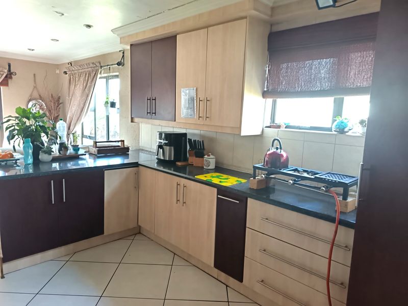 A functional kitchen featuring two-tone laminate cabinetry, granite countertops, and tiled flooring, offering a practical layout with ample storage space.