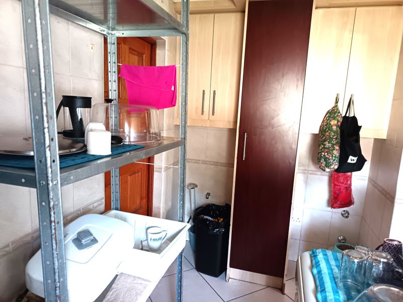 A functional scullery area featuring built-in cabinetry, tiled wall finishes, and dedicated plumbing connections for utility appliances.