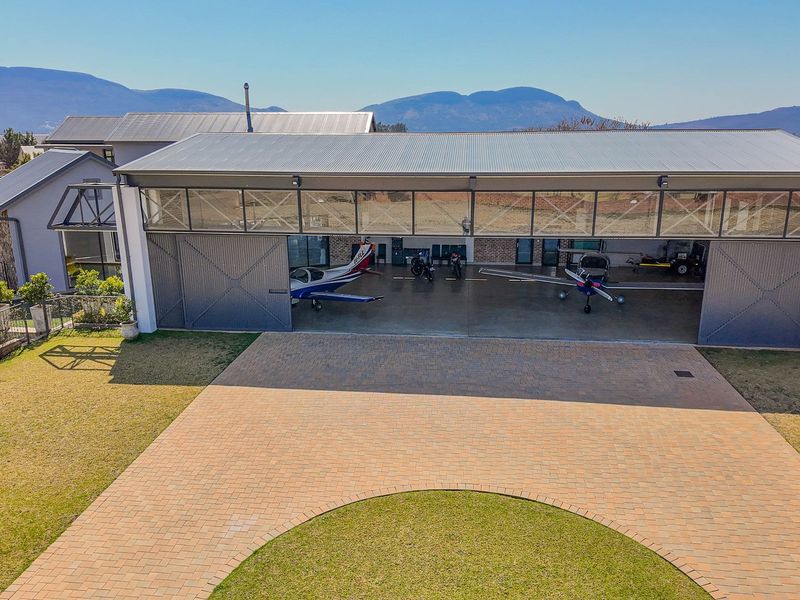 Spacious aircraft hangar or large garage featuring wide sliding doors, concrete flooring, and direct access to a paved driveway.