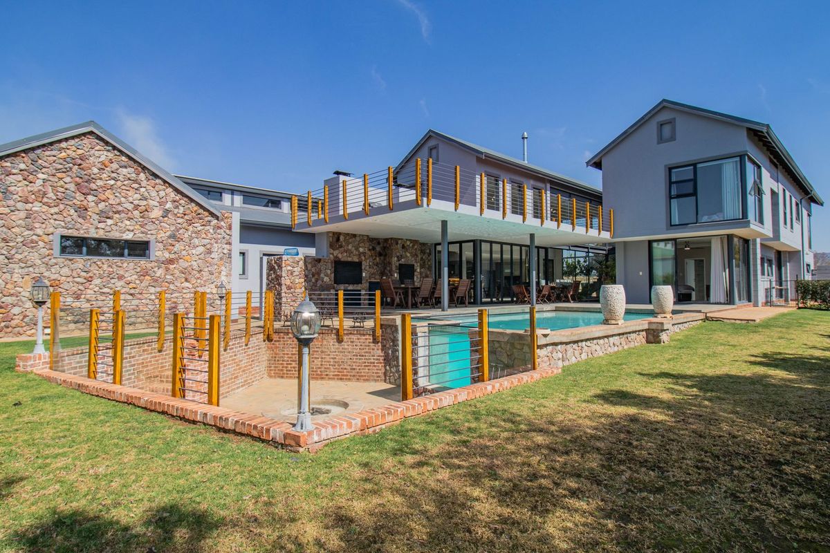 Spacious rear exterior featuring a swimming pool, sunken fire pit, covered patio, and balcony, showcasing modern architectural design with stone and brick finishes.
