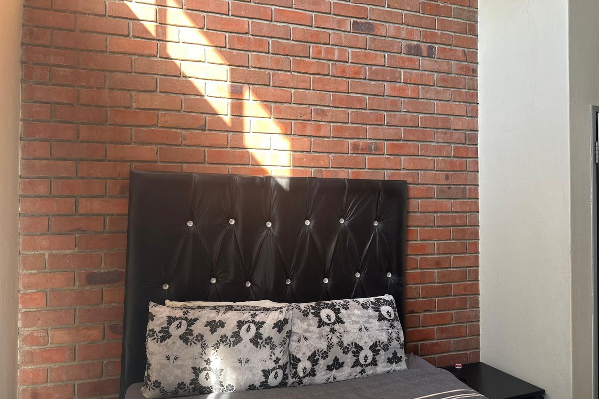 A bedroom featuring a prominent exposed red brick feature wall, providing a textured industrial aesthetic.