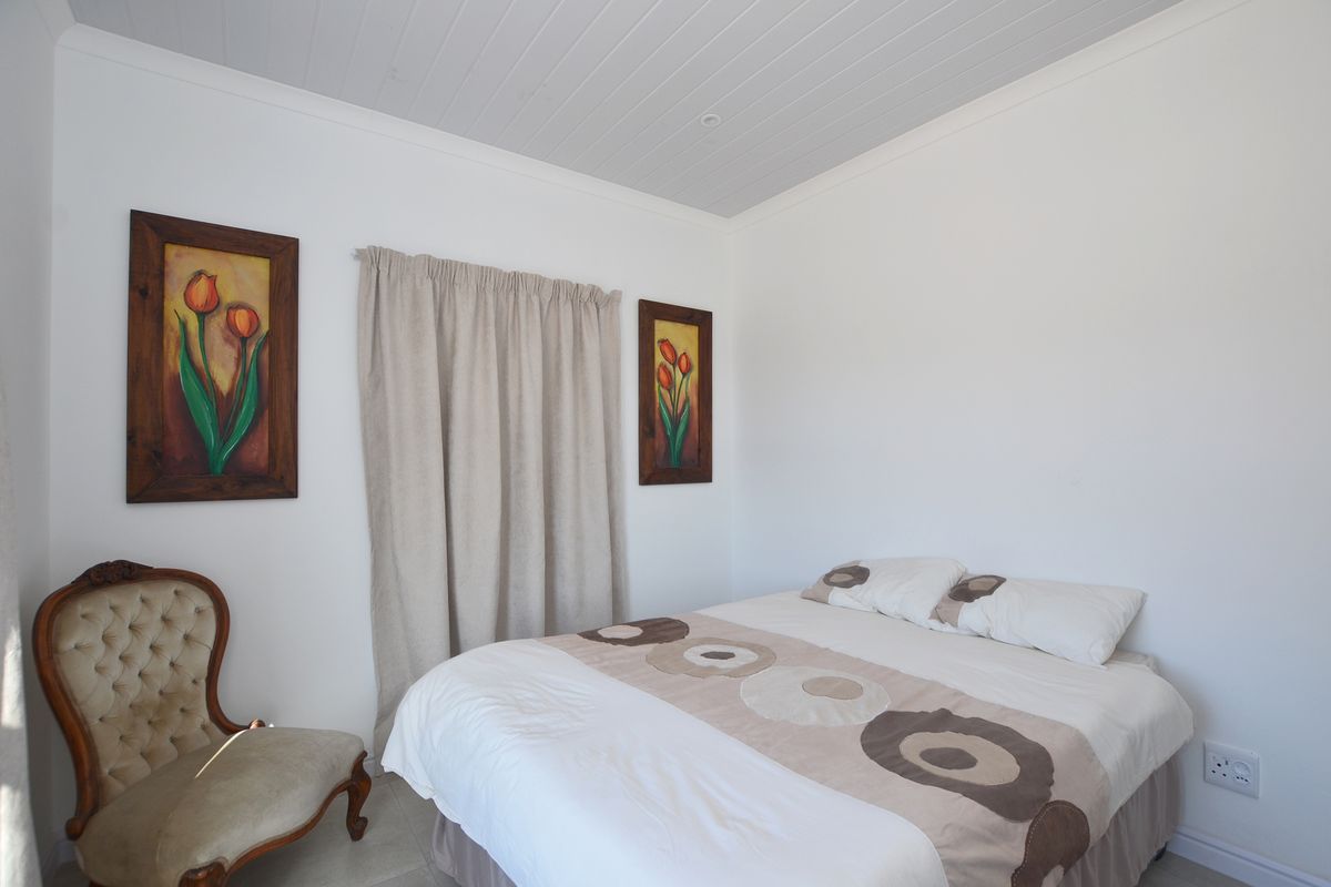 A well-maintained bedroom featuring white walls, a tongue-and-groove ceiling, and neutral tiled flooring.