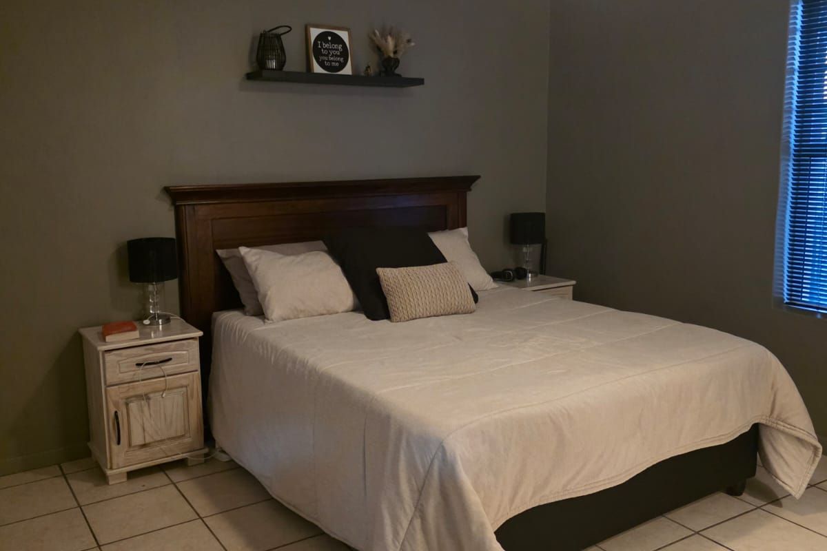 A bedroom featuring tiled flooring, a ceiling fan, and a built-in wooden headboard.