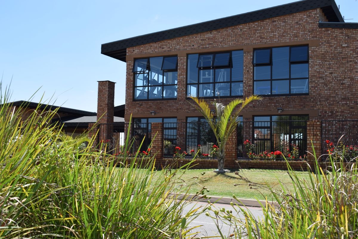 A view of the rear exterior facade featuring face brick construction, large aluminium windows, and a well-maintained garden area.