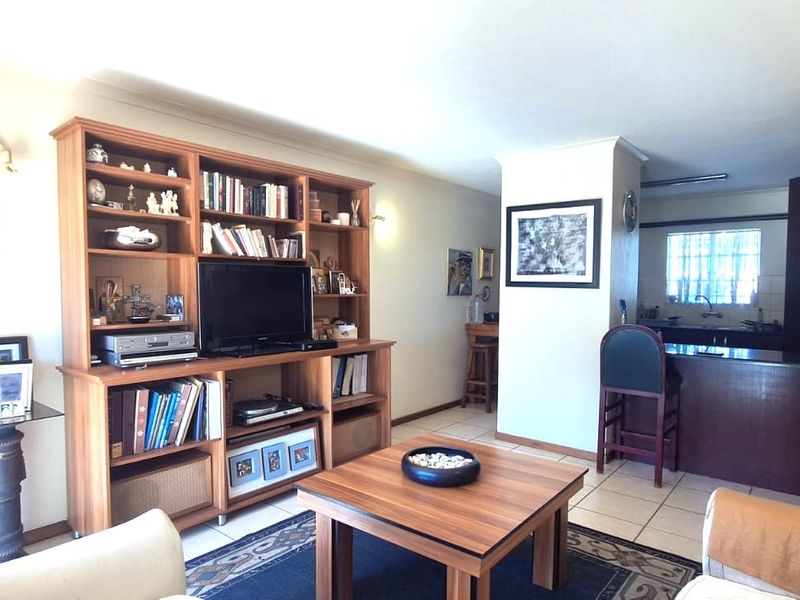 Open-plan living area featuring a kitchen with a breakfast bar and tiled flooring, seamlessly connecting to the main living space.