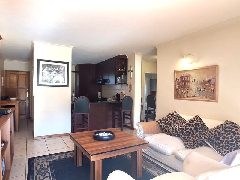 Open-plan living area featuring tiled flooring, built-in cabinetry, and a breakfast bar connecting to the kitchen space.