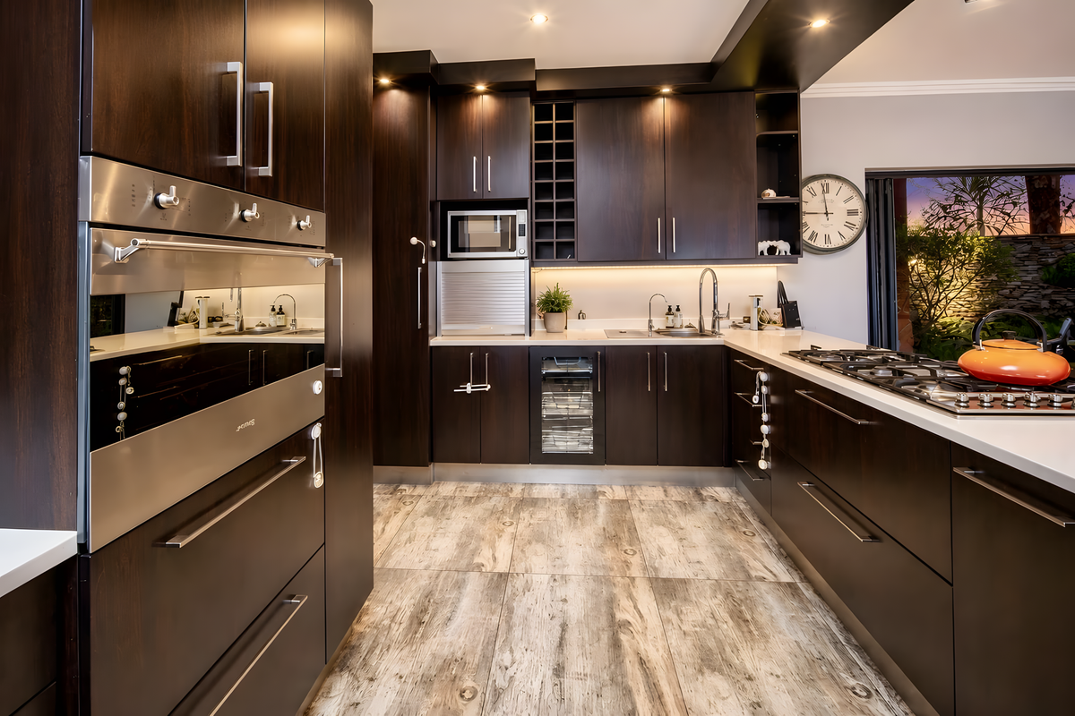 Modern kitchen featuring dark wood cabinetry, stone countertops, integrated stainless steel appliances, a gas hob, and a built-in wine cooler.