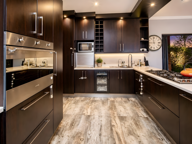 Modern kitchen featuring dark wood cabinetry, stone countertops, integrated stainless steel appliances, a gas hob, and a built-in wine cooler.
