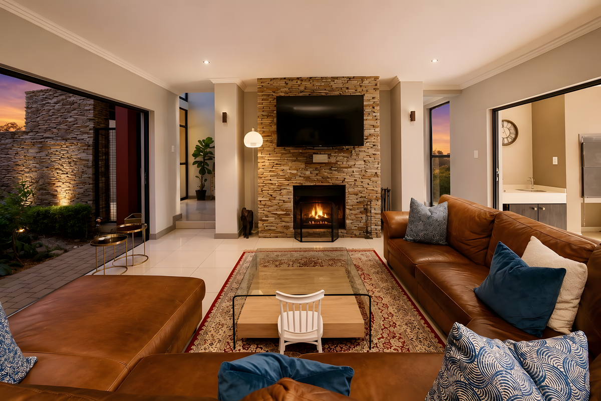 Spacious living room featuring a prominent stone-clad fireplace, large sliding doors opening to an outdoor area, and modern recessed lighting.