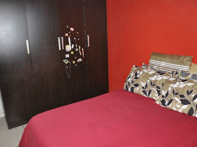 A bedroom featuring a dark wood built-in wardrobe and a bold red accent wall.