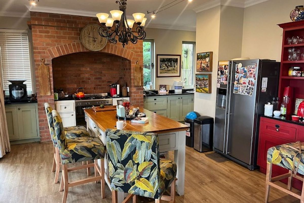 A spacious kitchen featuring a prominent brick feature wall with a built-in oven, central island, and ample cabinetry with granite countertops.