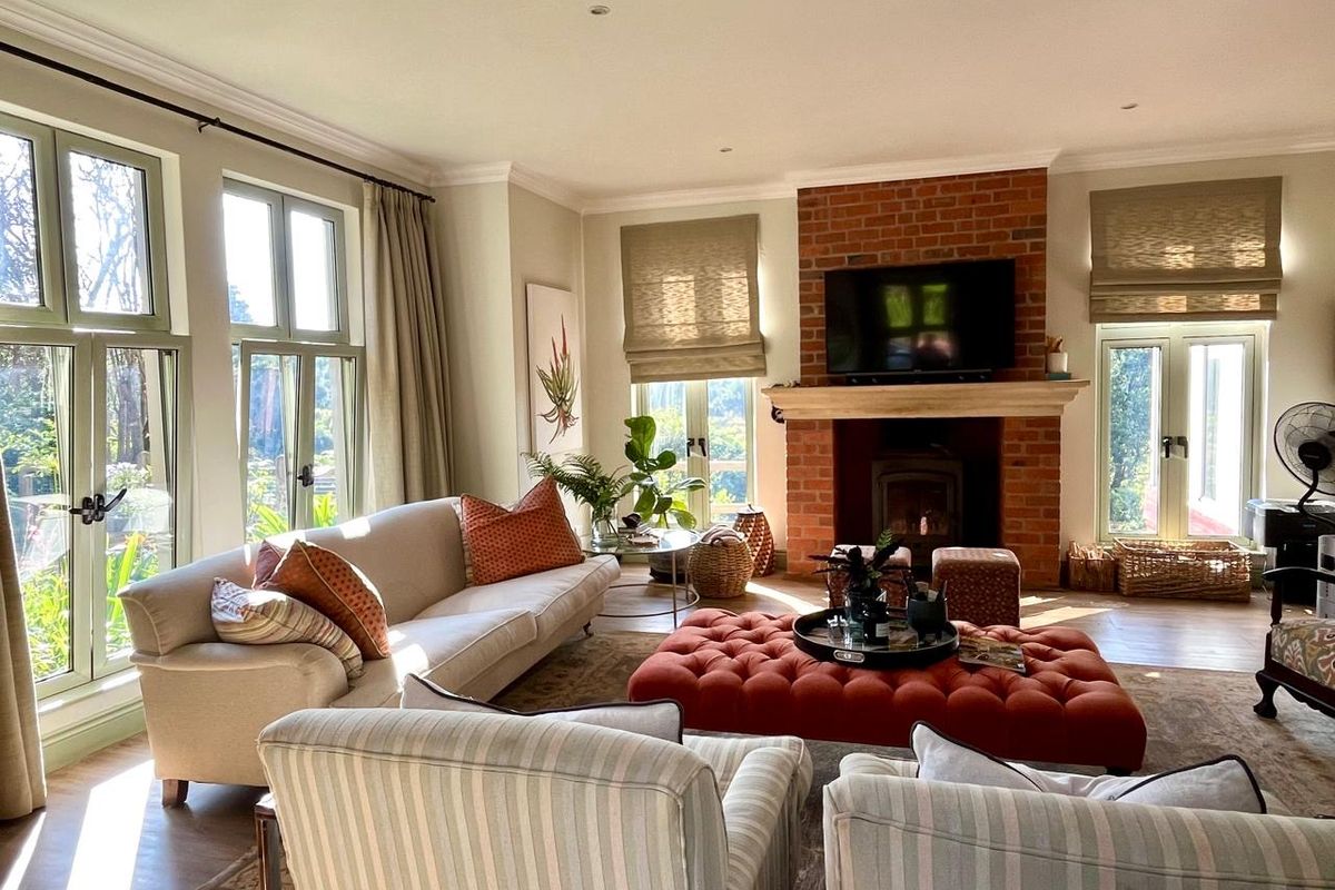 Spacious living room featuring a classic brick fireplace with a wood-burning stove, large casement windows, and elegant crown molding.