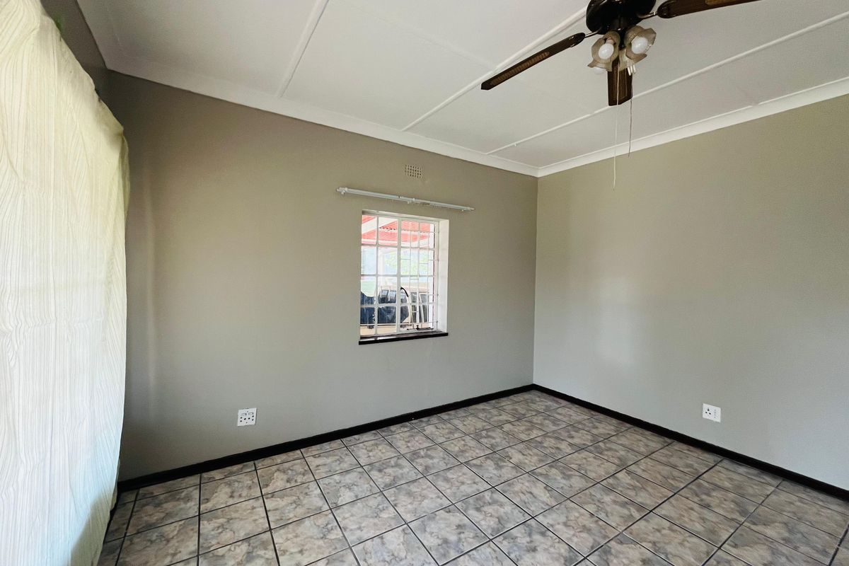 An empty bedroom featuring neutral wall paint, tiled flooring, and a ceiling fan, providing a clean and versatile space ready for furnishing.