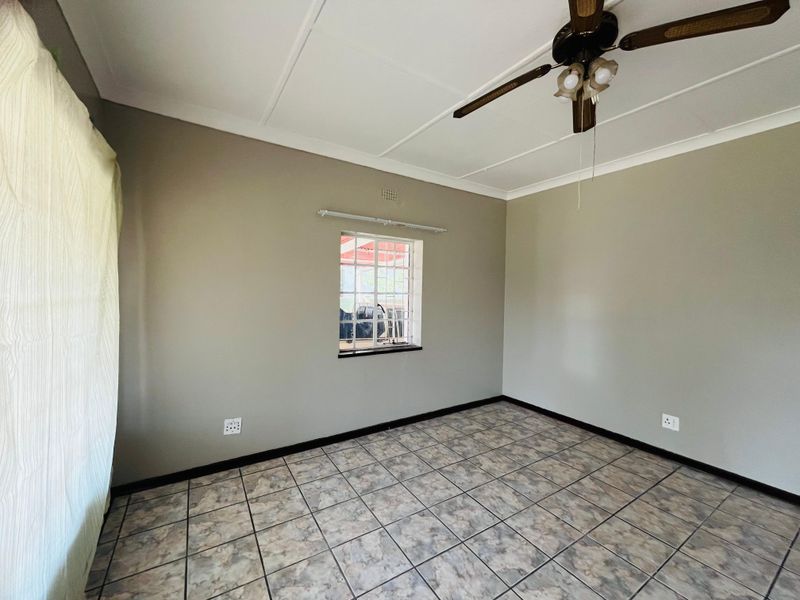 An empty bedroom featuring neutral wall paint, tiled flooring, and a ceiling fan, providing a clean and versatile space ready for furnishing.