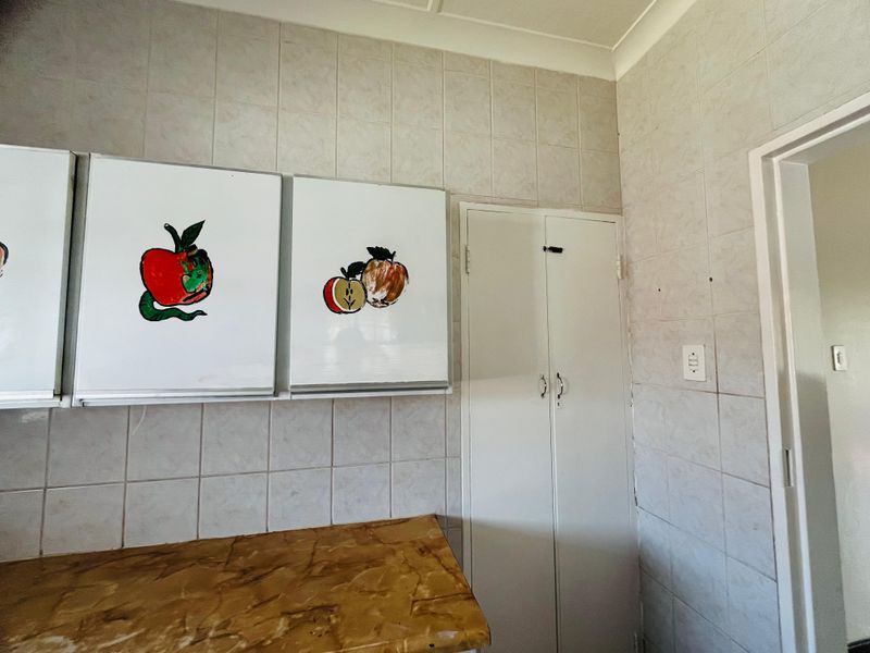 A dated kitchen area featuring tiled walls, built-in cabinetry, and a laminate countertop, offering potential for a modern renovation.
