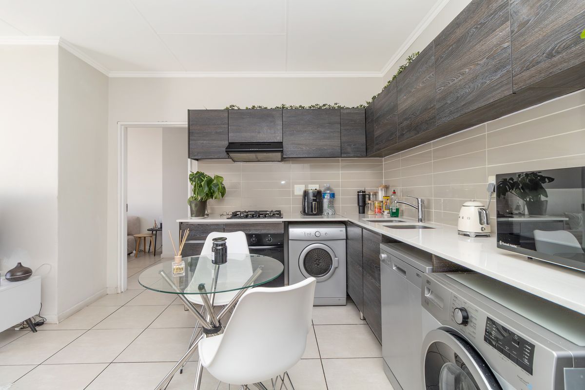 Modern kitchen featuring dark wood cabinetry, white stone countertops, subway tile backsplash, and integrated appliances including a gas hob and oven.