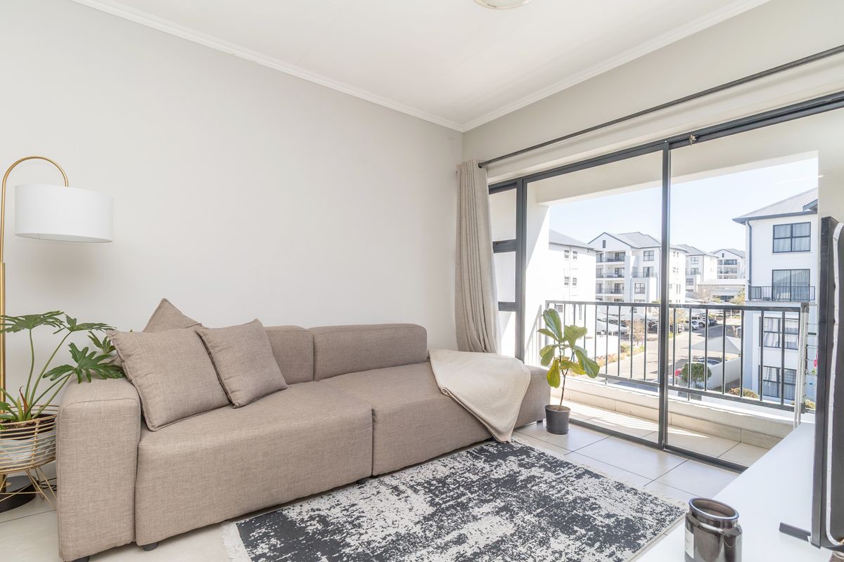 A bright and modern living room featuring tiled flooring and large sliding glass doors that provide access to a private balcony.