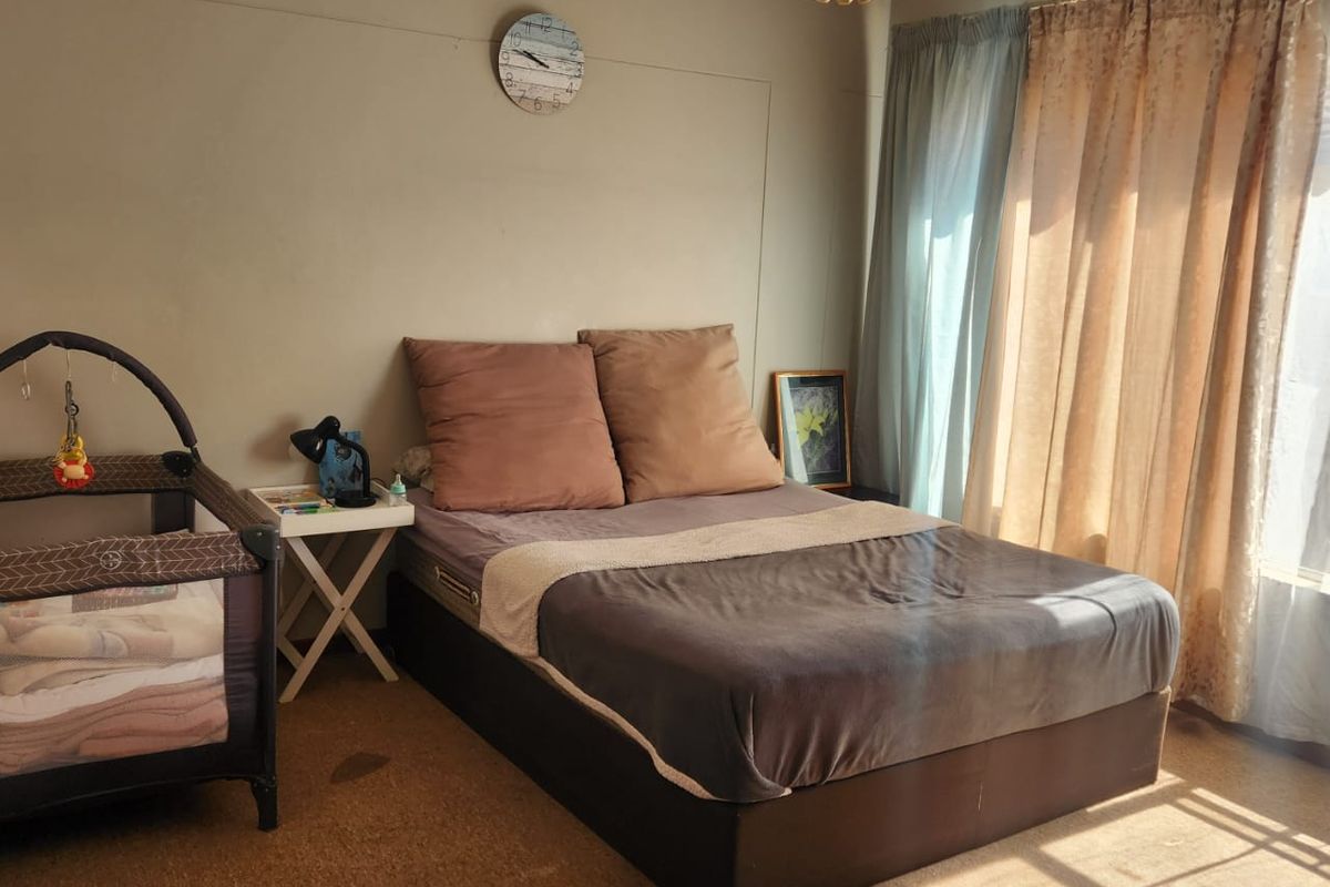 A bedroom featuring carpeted flooring and a central pendant light fixture, currently utilized as a sleeping space.
