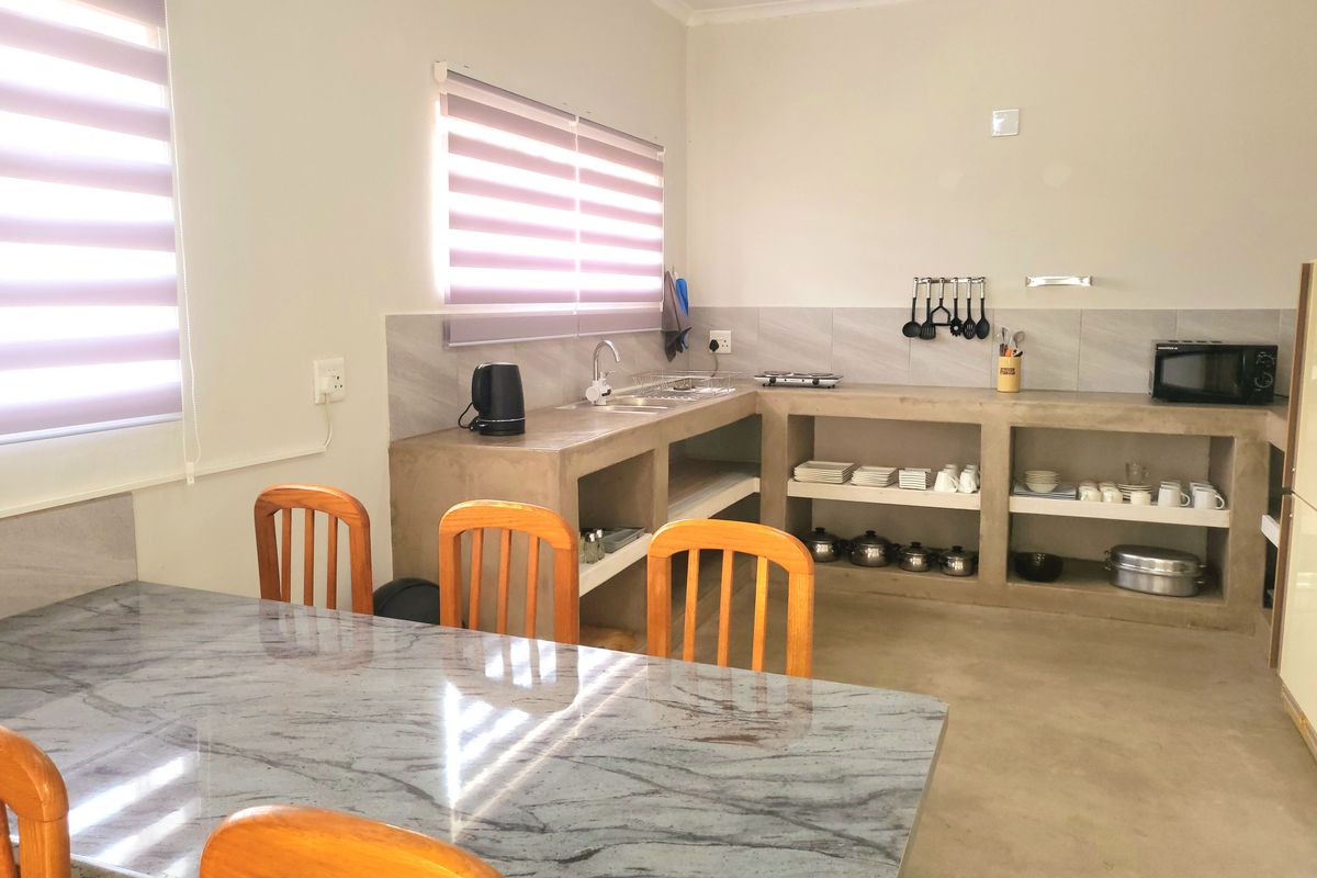 A functional kitchen featuring custom concrete countertops, open shelving, and a tiled splashback, providing a clean and industrial-style workspace.