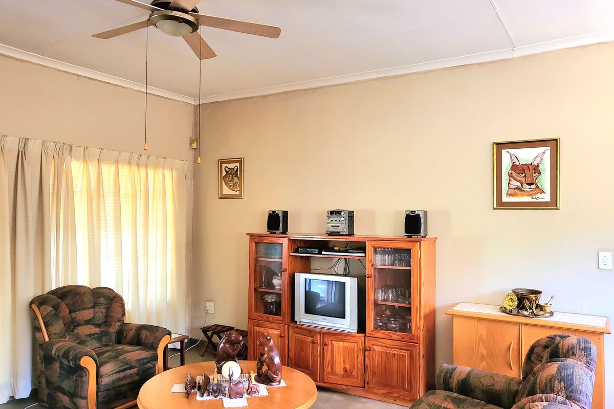 A living room featuring a ceiling fan and neutral wall finishes, providing a functional space for relaxation.
