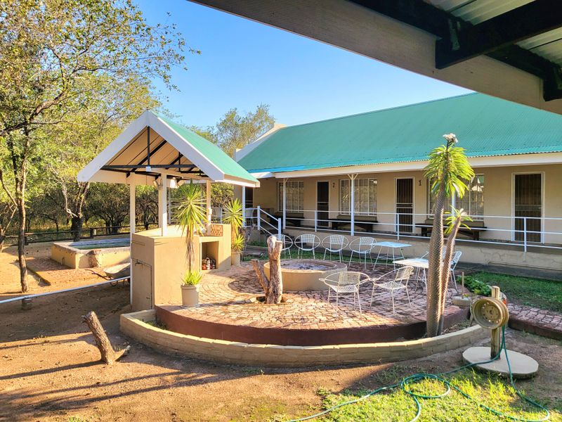 Outdoor entertainment area featuring a built-in braai, central fire pit, and paved patio space adjacent to the main building structure.