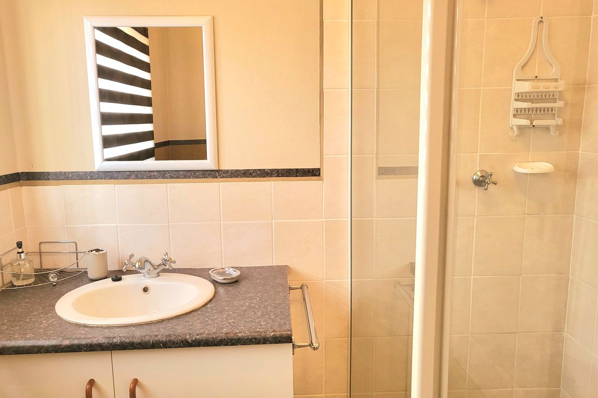 A functional bathroom featuring a vanity with a drop-in sink, tiled walls, and a glass-enclosed shower stall.