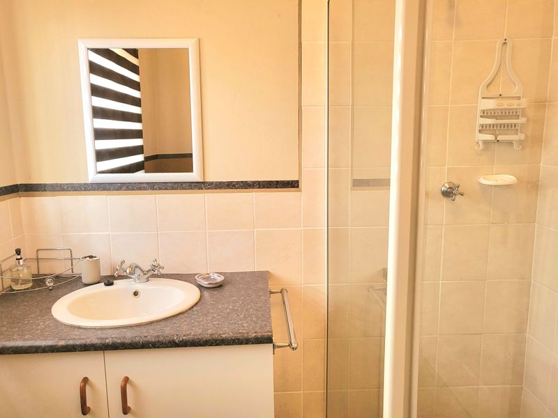 A functional bathroom featuring a vanity with a drop-in sink, tiled walls, and a glass-enclosed shower stall.