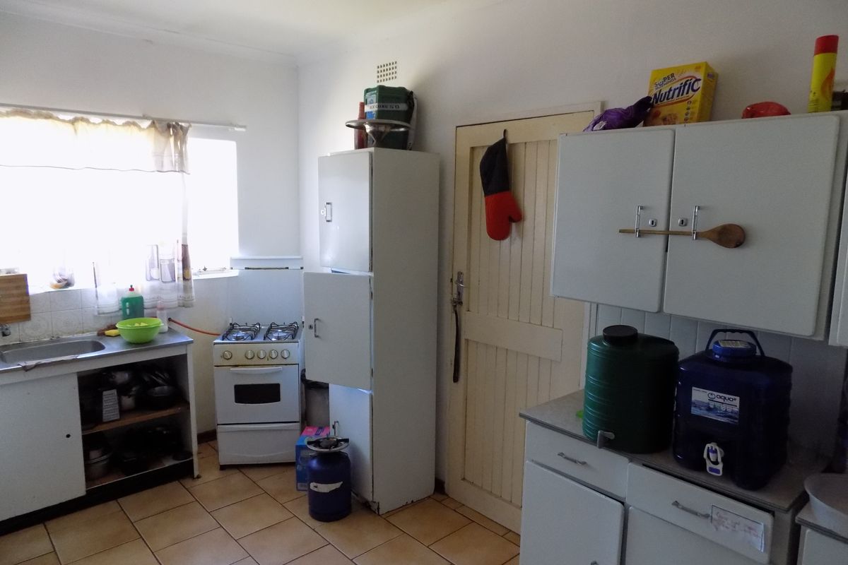 A functional kitchen featuring tiled flooring, built-in cabinetry, a gas stove, and a stainless steel sink, offering potential for modernization.