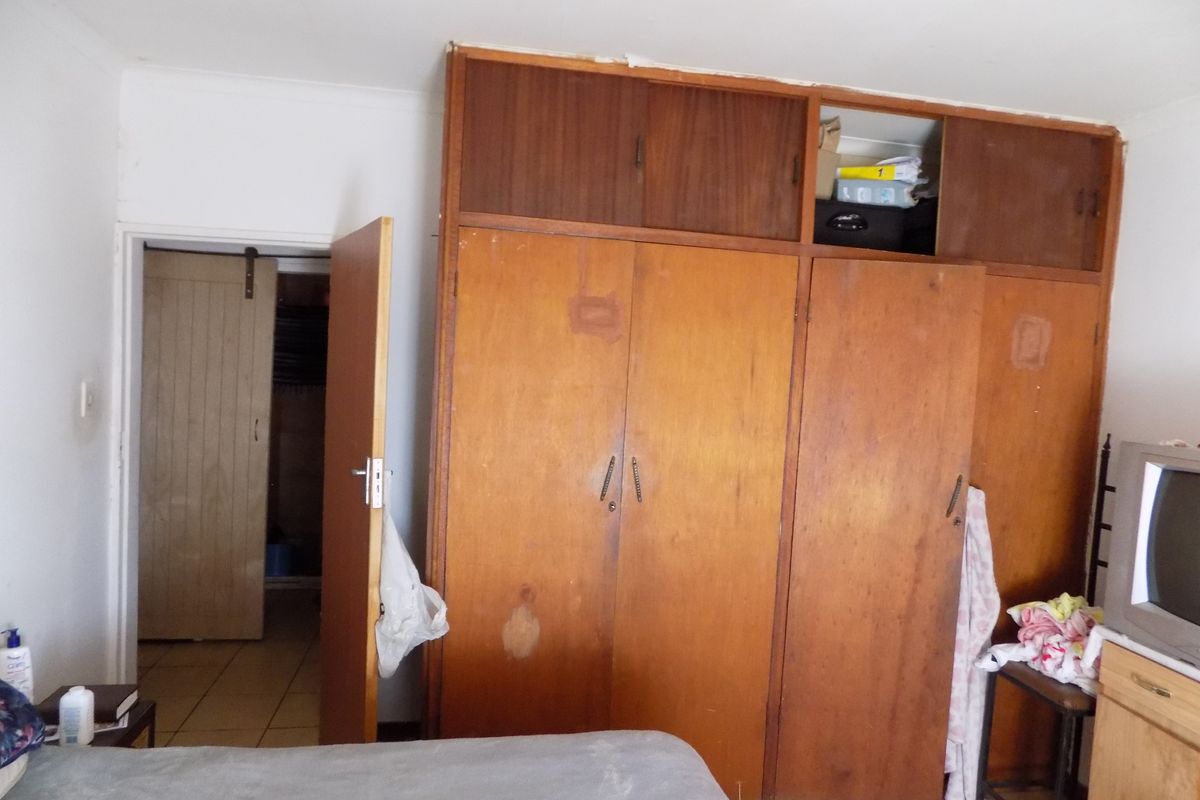 Bedroom featuring extensive built-in wooden cabinetry with overhead storage and tiled flooring, leading to an adjacent walk-in closet area.