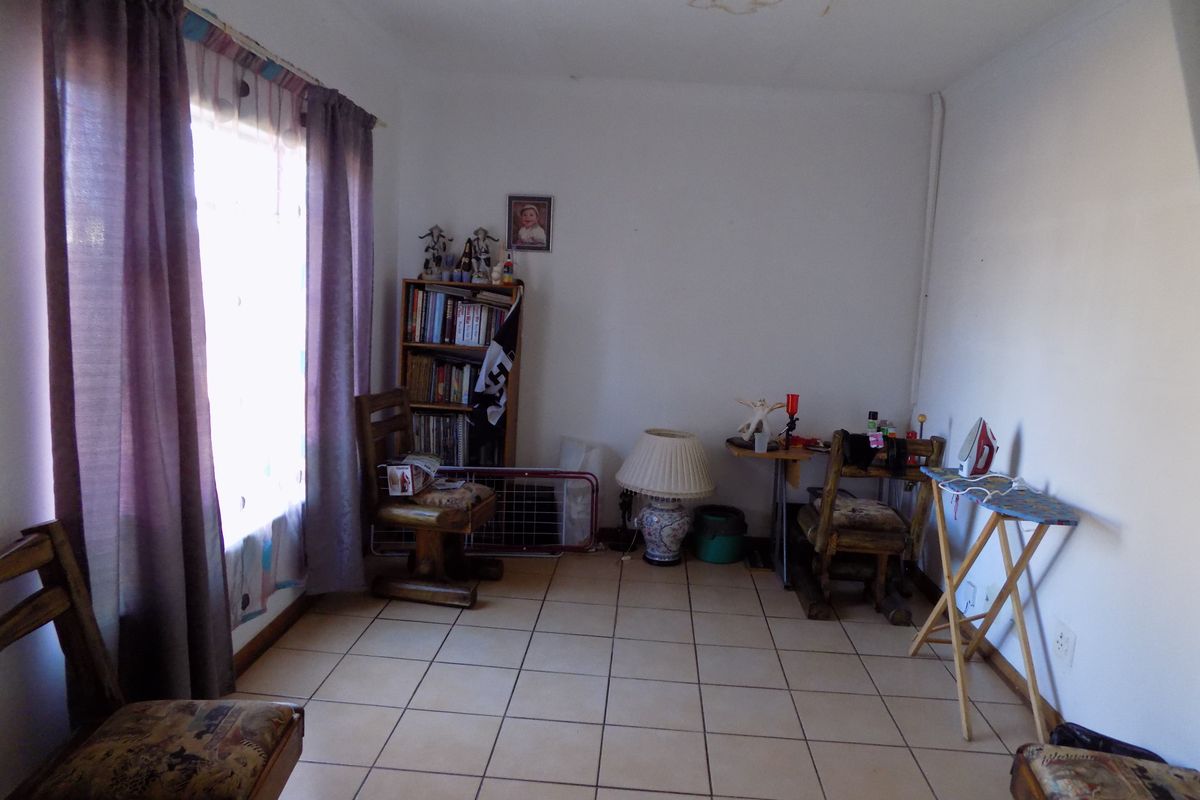 A living area featuring ceramic floor tiles and a visible water stain on the ceiling.