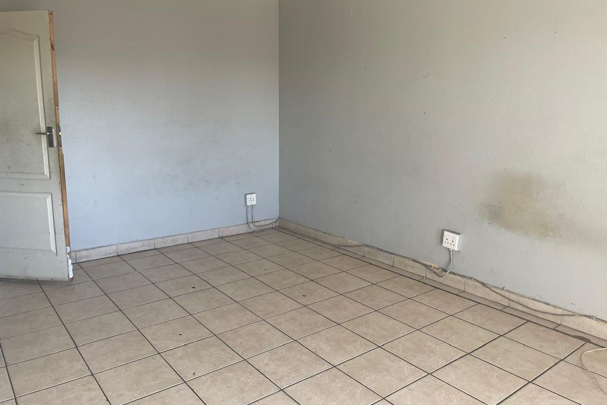 An empty room featuring tiled flooring, neutral walls with visible wear, and standard electrical outlets, ready for renovation or personalization.