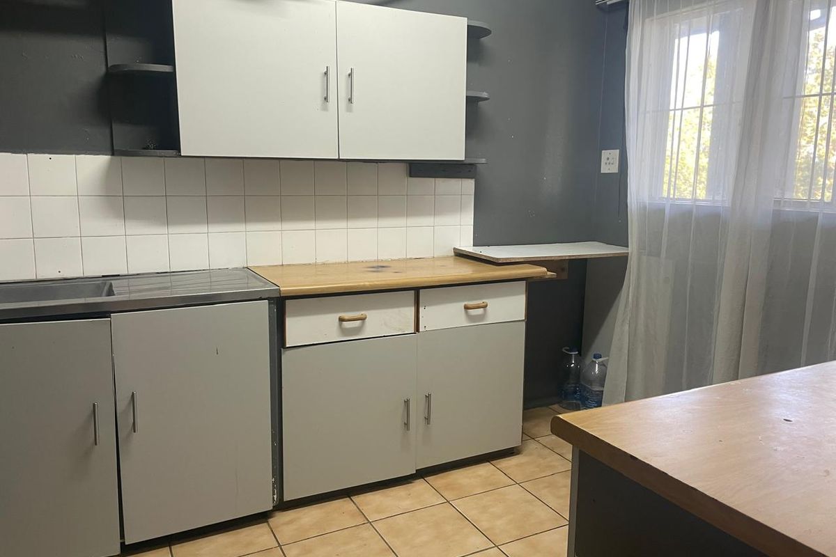 A functional kitchen area featuring built-in cabinetry, tiled splashbacks, and tiled flooring, offering a practical layout for renovation or modernization.