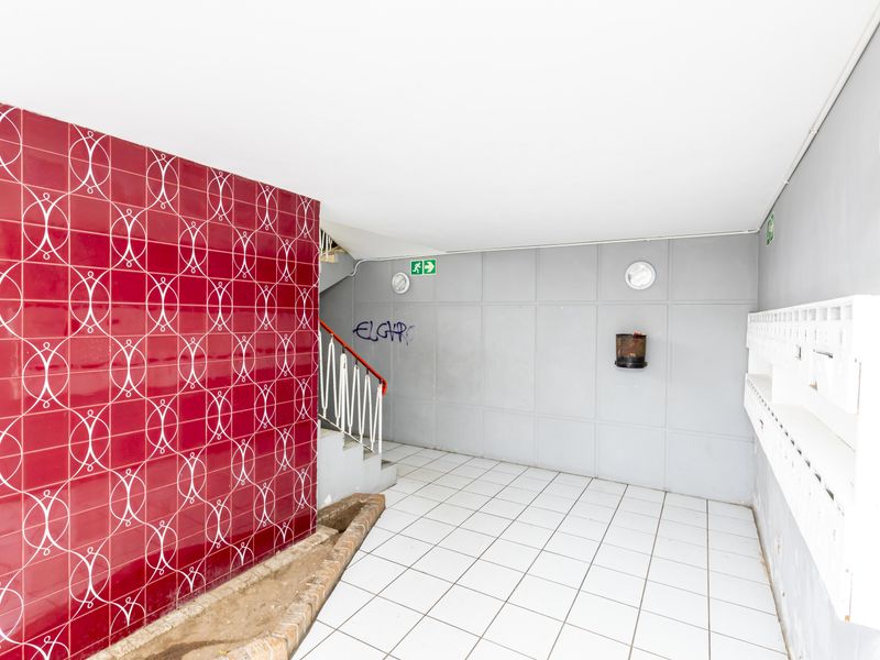 Communal apartment building entrance lobby featuring tiled flooring, a decorative red tiled feature wall, and integrated mailboxes.