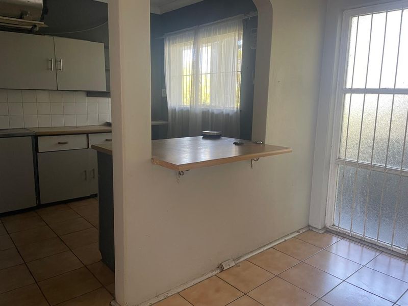 A functional kitchen area featuring a breakfast bar pass-through, tiled flooring, and built-in cabinetry, providing a practical layout for daily living.