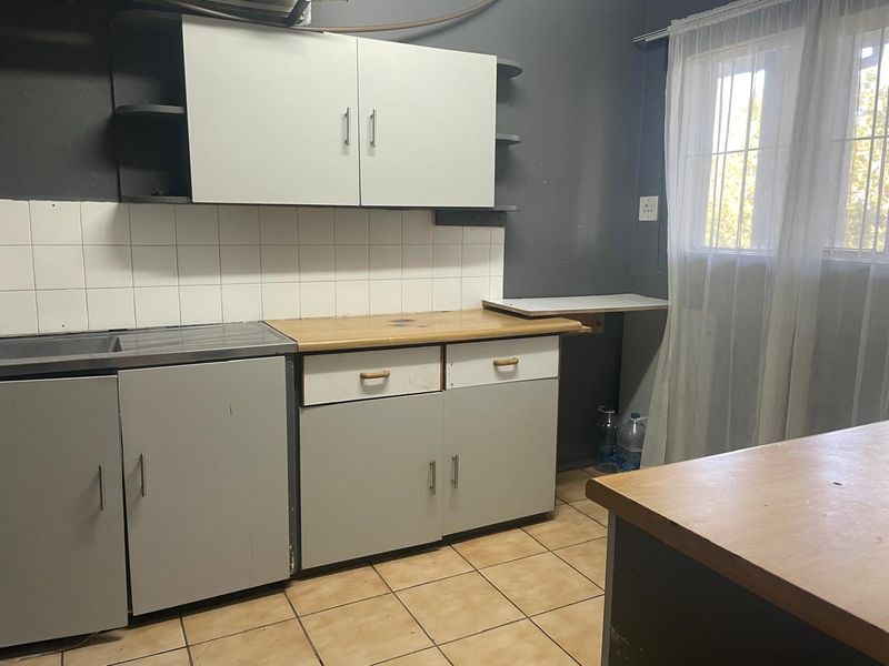 A functional kitchen area featuring built-in cabinetry, tiled splashbacks, and tiled flooring, offering a practical layout for renovation or modernization.