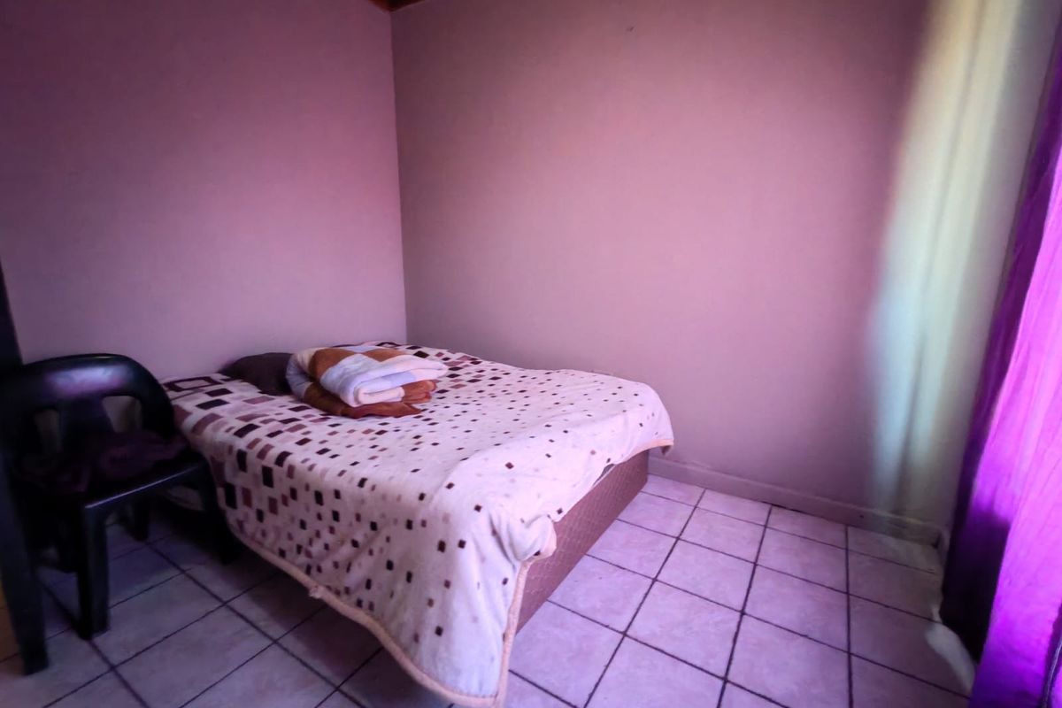 A simple bedroom featuring tiled flooring and a timber ceiling, requiring cosmetic updates to improve the overall aesthetic and finish.