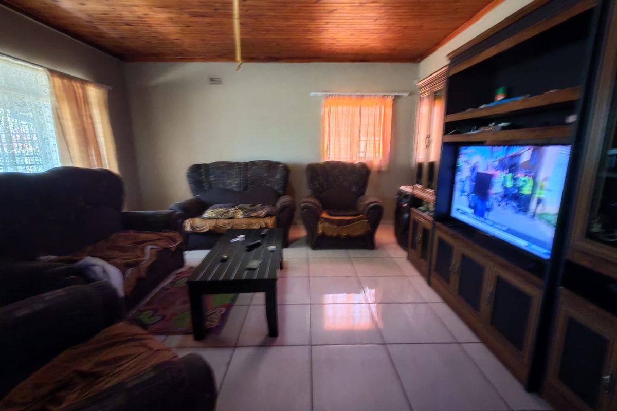 Living room featuring a timber tongue and groove ceiling, ceramic tiled flooring, and a large built-in wooden entertainment unit.