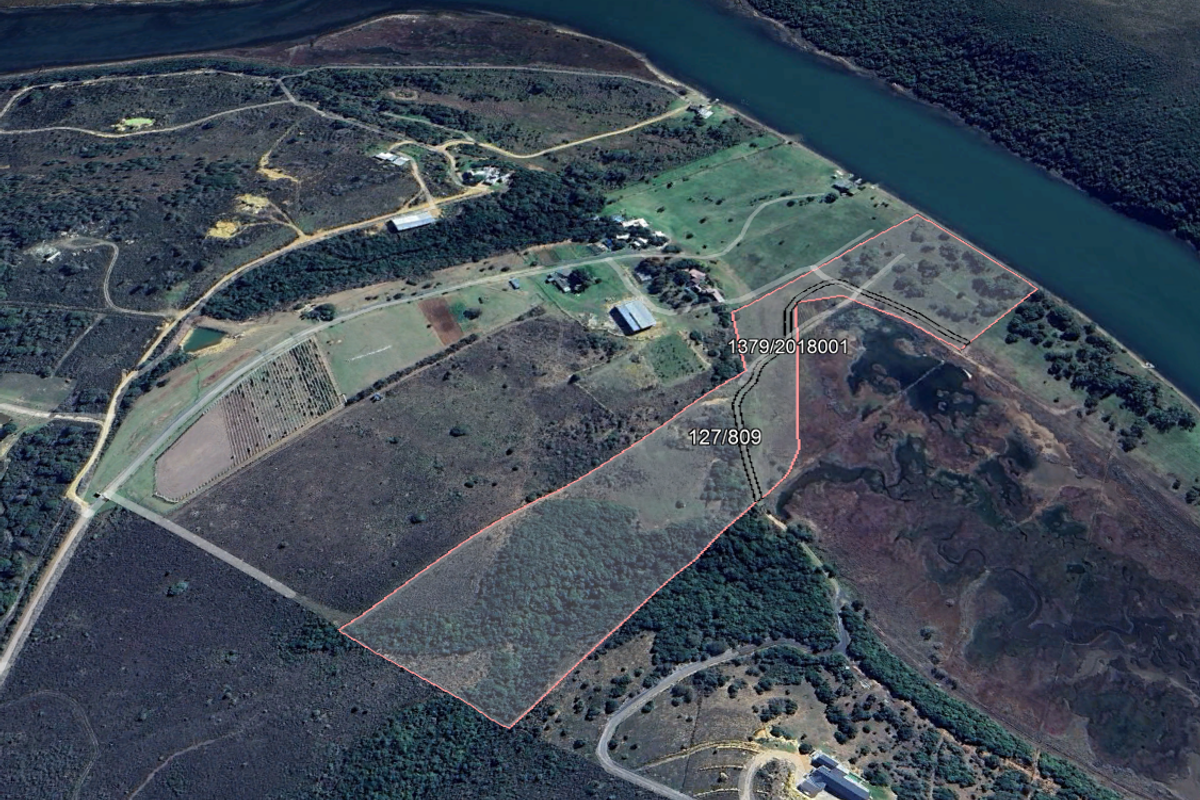 Aerial view of a large vacant residential plot featuring natural landscape, river frontage, and clear boundary demarcations.