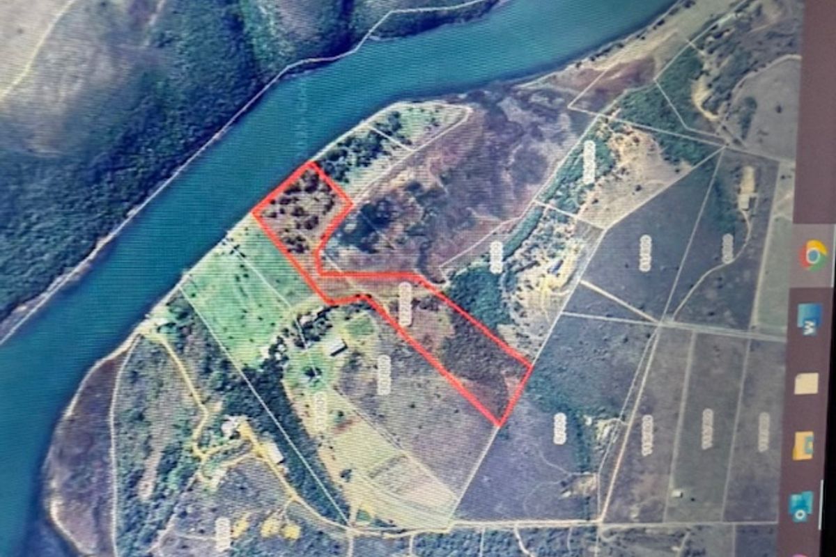 Aerial view of a vacant residential land parcel featuring river frontage and natural vegetation.