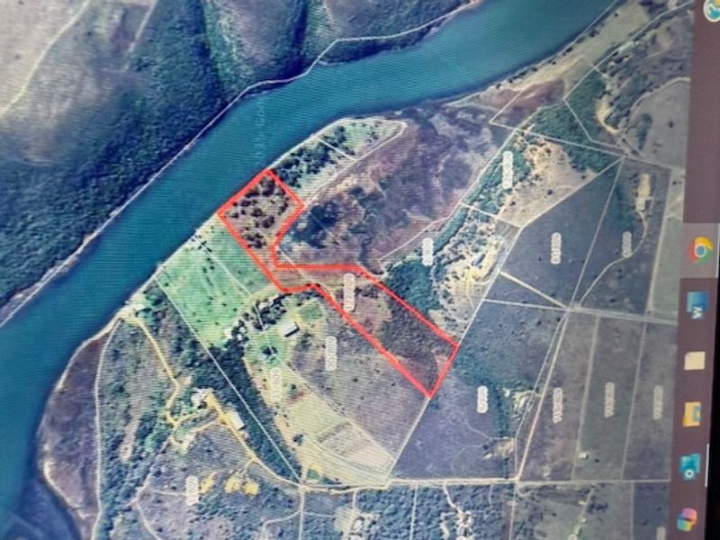 Aerial view of a vacant residential land parcel featuring river frontage and natural vegetation.