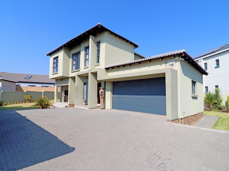A well-maintained double-story residential property featuring a paved driveway, integrated double garage, and modern plastered exterior finishes.