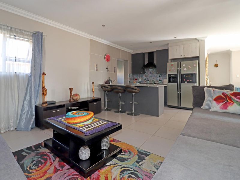 Open-plan living area featuring a modern kitchen with a central island, tiled flooring, and recessed lighting, creating a functional and connected space.