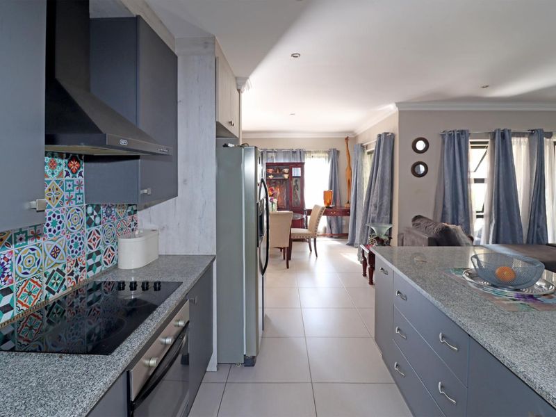 Modern open-plan kitchen featuring granite countertops, built-in appliances, and a central island, flowing seamlessly into the adjacent living and dining area.
