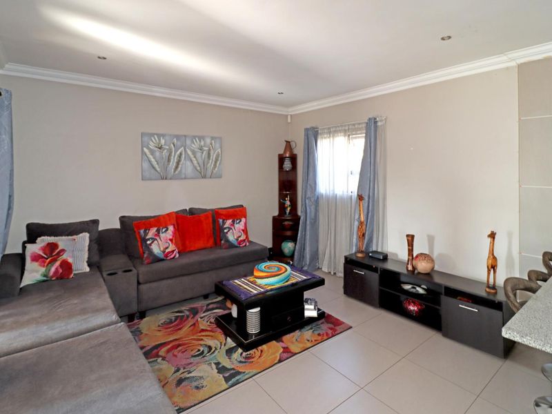 A well-maintained living room featuring neutral wall tones, tiled flooring, and recessed downlighting, providing a comfortable and functional space.