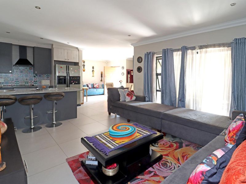 Spacious open-plan living area featuring a modern kitchen with a central island, granite countertops, and seamless flow to the lounge with large sliding doors.
