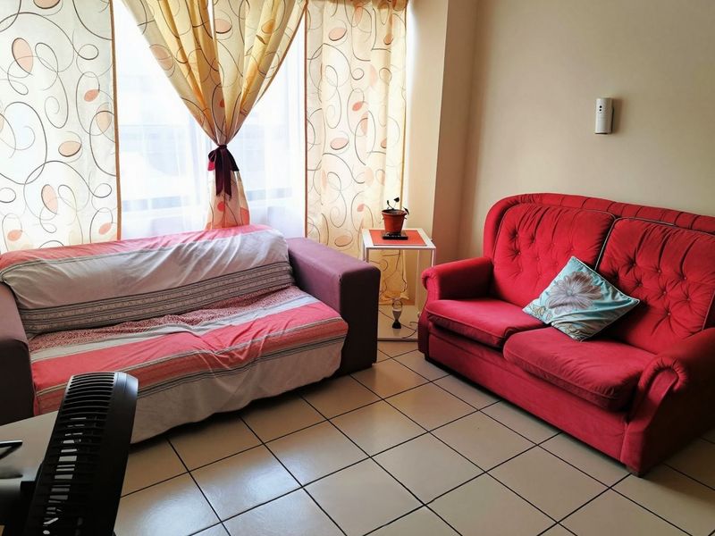 A living room area featuring tiled flooring and a large window with natural light.