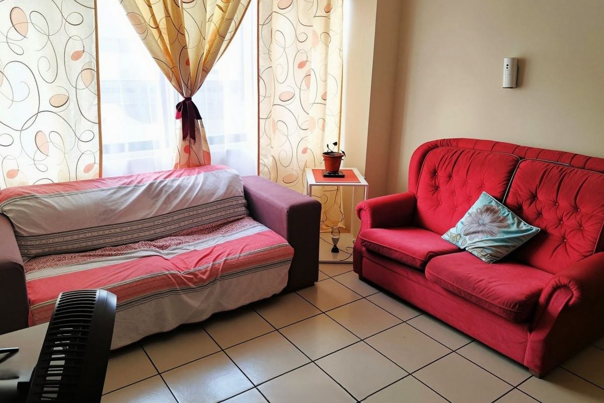 A living room area featuring tiled flooring and a large window with natural light.